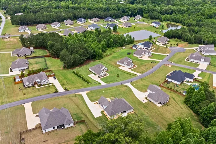 An aerial perspective reveals a serene residential community with verdant landscaping and views of the pond.