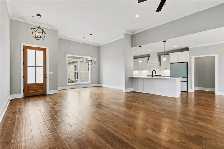 Hardwood floors stretch across this open-concept layout, connecting the living area and dining area to a modern kitchen.