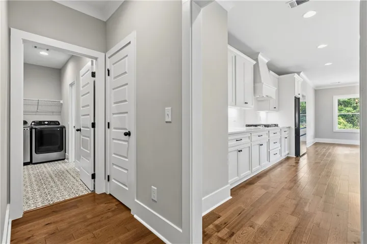 Hardwood floors guide you from a practical laundry area to a bright, well-appointed kitchen.