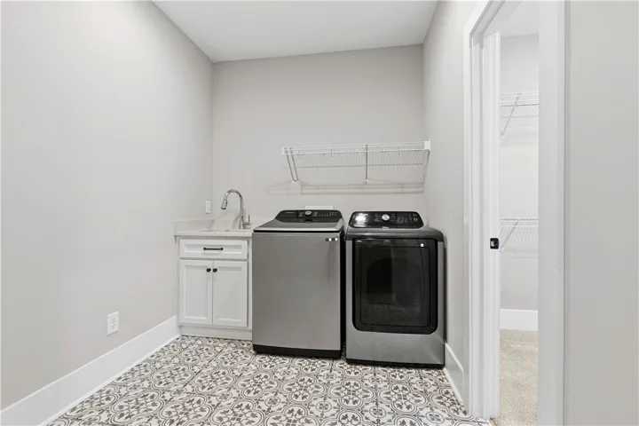 Functional laundry room featuring a utility sink for convenience and cute tiles!