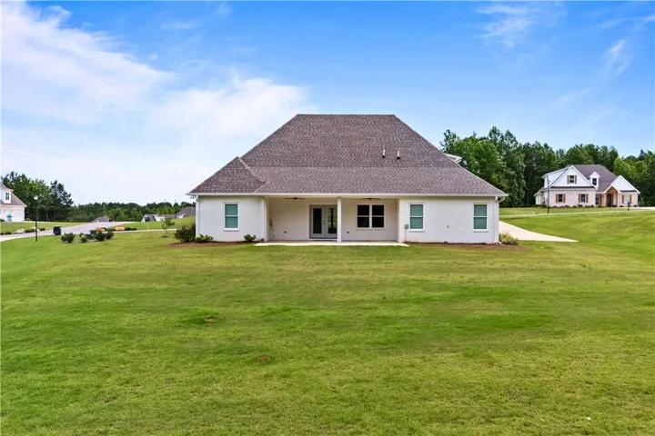 A sprawling green lawn unfurls behind this charming residence, perfect for outdoor activities and serene relaxation.