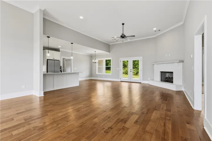 Hardwood floors stretch across a light-filled open-concept space featuring a sleek kitchen and a cozy fireplace.