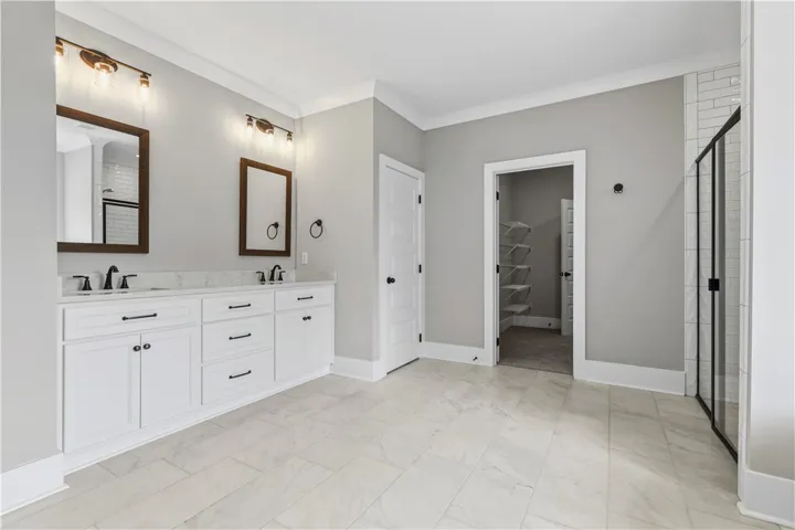 A well-appointed primary bathroom showcases dual vanities, elegant tile flooring, and convenient access to a walk-in closet and a separate shower and bathtub.