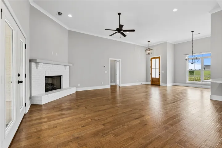 Hardwood flooring flows through this expansive living area, highlighted by a whitewashed brick fireplace and generous windows.