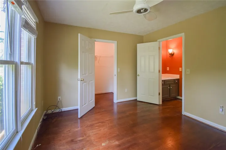 Rich hardwood flooring complements a bedroom with an adjoining closet and private vanity area.