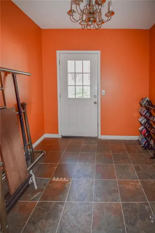 A graceful chandelier illuminates the tiled floor leading to an exterior access door.