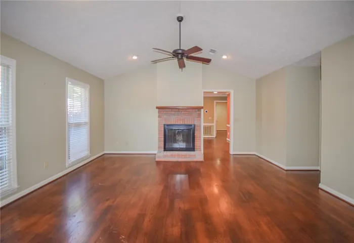 Vast hardwood floors stretch across this living space, centered around a charming brick fireplace.