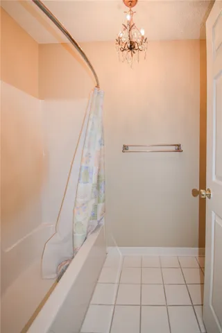 Elegant chandelier lighting graces this well-appointed bath with tiled flooring.