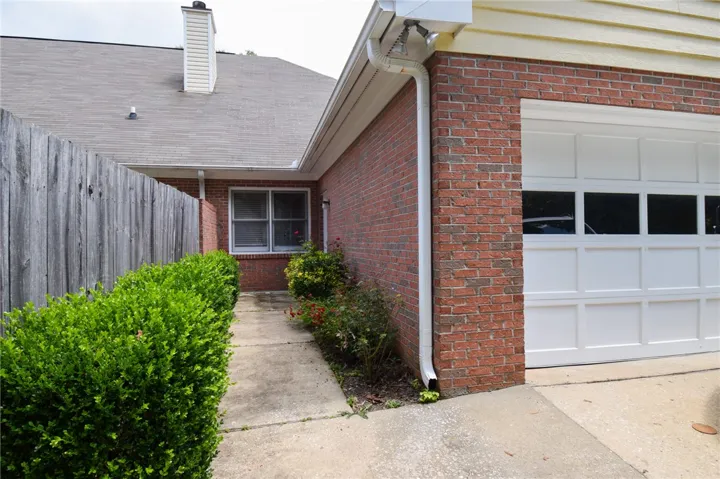 A classic brick exterior with a well-maintained white garage door and neatly trimmed landscaping.