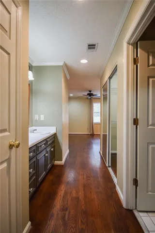 Rich hardwood floors guide you down this hallway to a bright, inviting room.