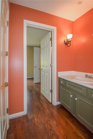 Rich hardwood floors complement vibrant walls in this well-appointed bathroom with a classic vanity.