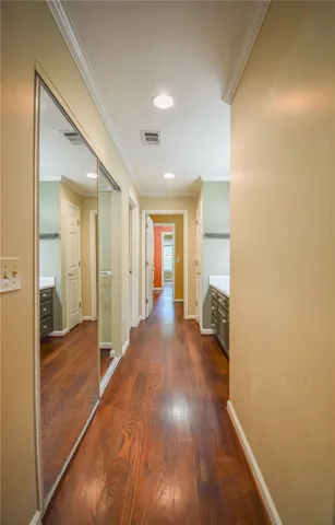 A long, inviting hallway showcases rich hardwood flooring and sleek mirrored closet doors.
