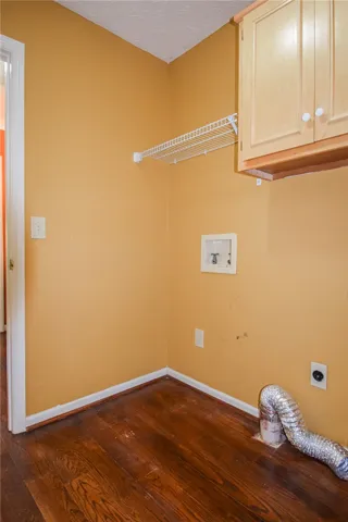 A well-appointed laundry room awaits your appliances, featuring durable wood flooring and practical cabinetry for storage.