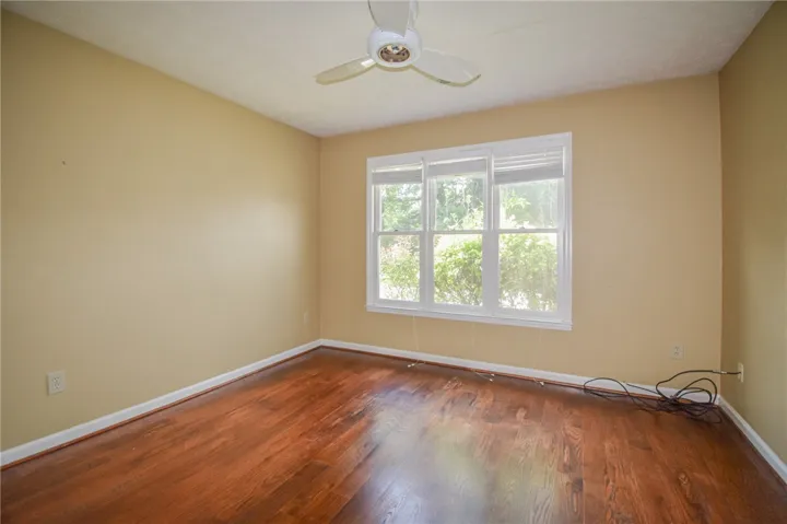 Well-lit room with warm wooden floors and a ceiling fan, perfect for a comfortable living space.