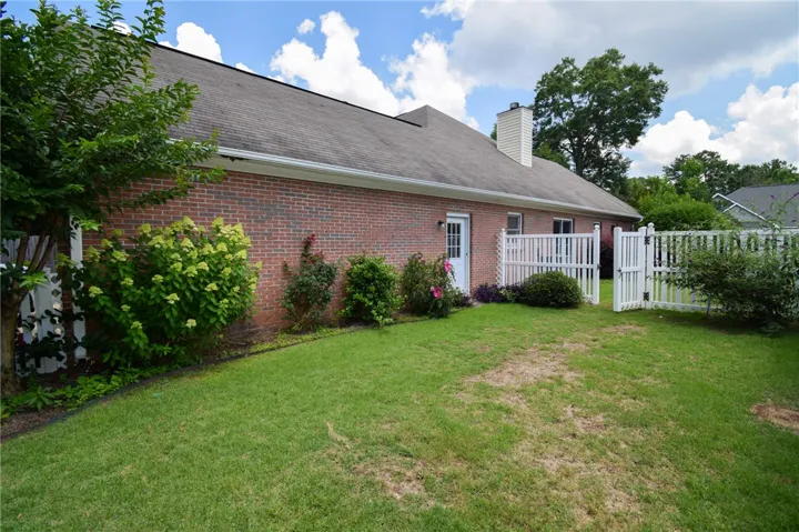 Mature landscaping and white picket fencing enclose a private lawn space at the side of this charming brick residence.