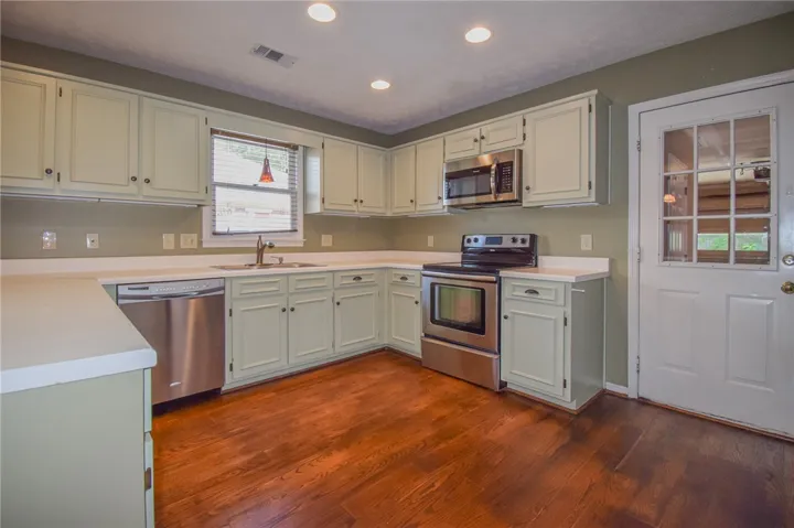 A well-lit kitchen with classic cabinetry and durable wood flooring awaits culinary creations.