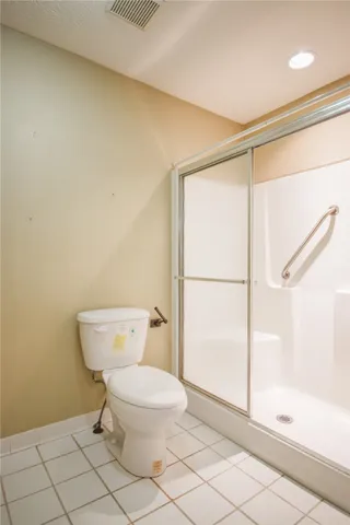 Tiled flooring and a practical shower with grab bar enhance this bathroom's utility.