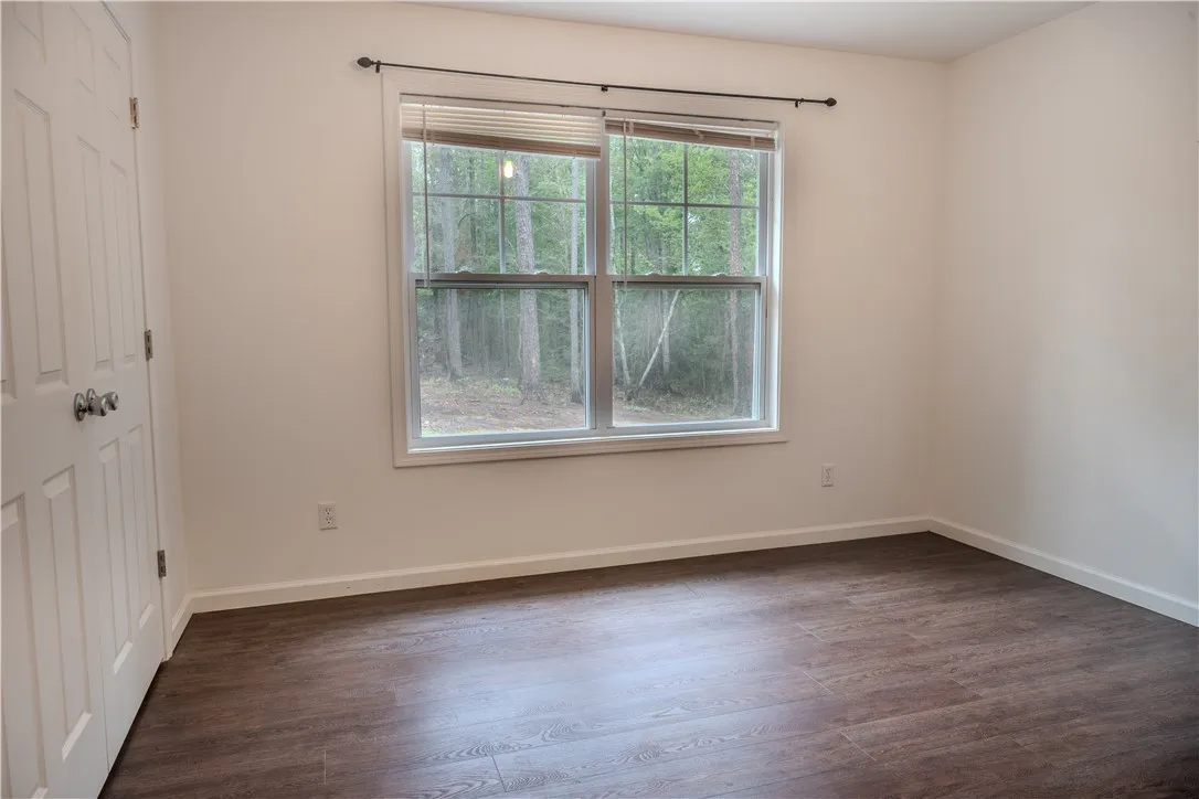 Ample natural light illuminates rich hardwood flooring in this cozy bedroom.