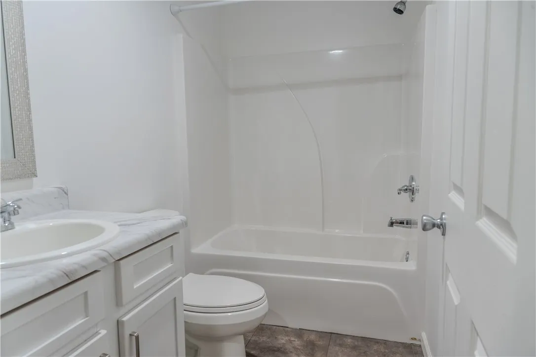 A well-appointed bathroom offers a clean tub-shower combination, modern vanity, and practical flooring.