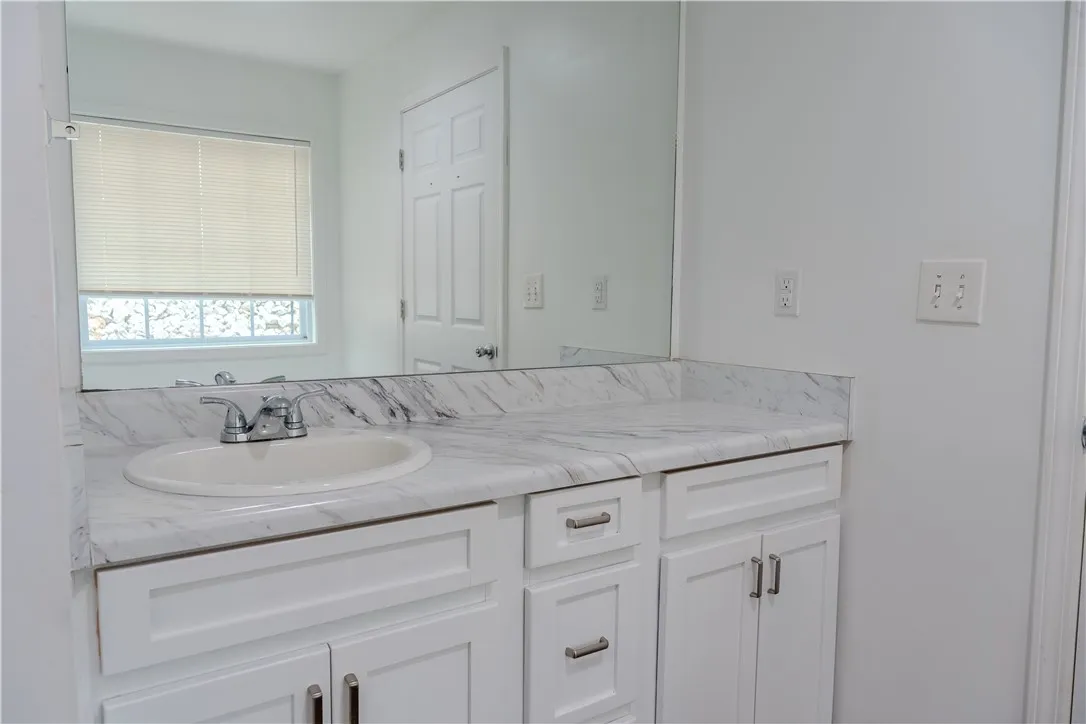 White cabinetry provides ample storage beneath a sleek, marbled vanity in this updated primary bathroom.