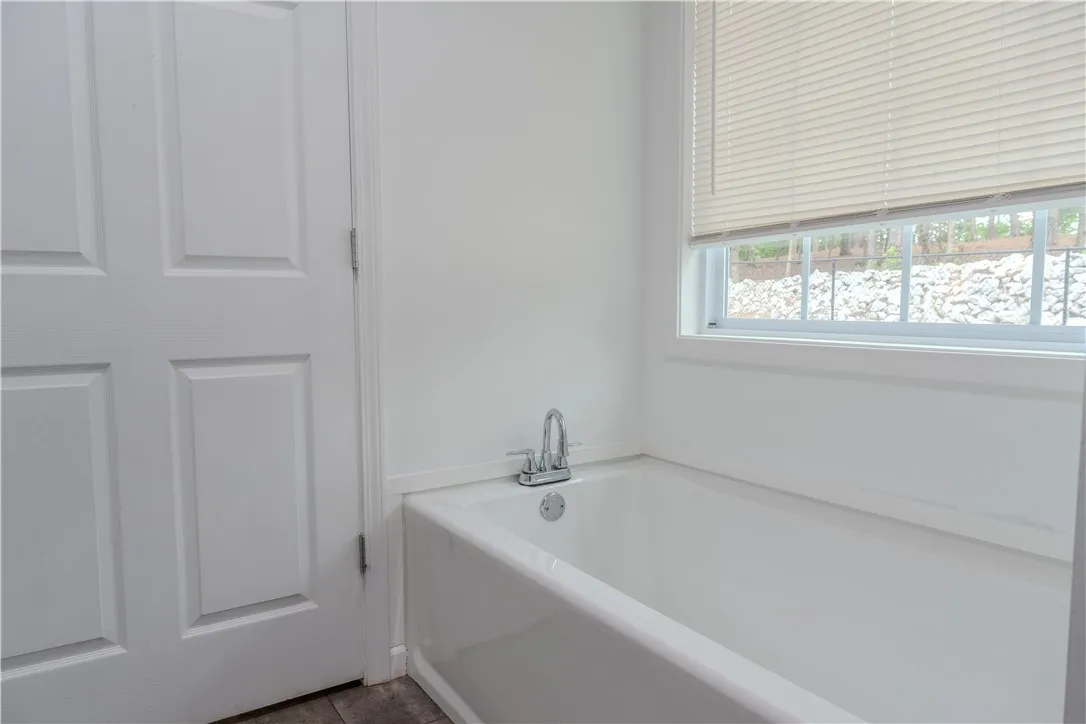 A pristine white bathtub offers a clean, inviting space with a window above.