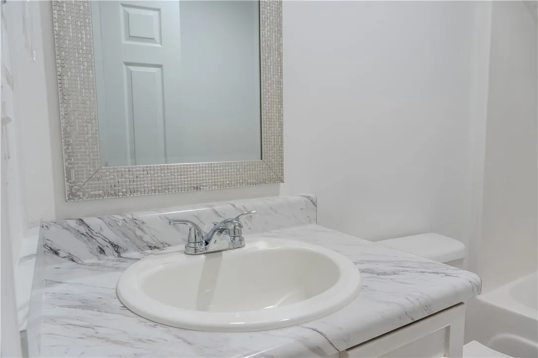A well-appointed bathroom features a practical vanity and a classic framed mirror.