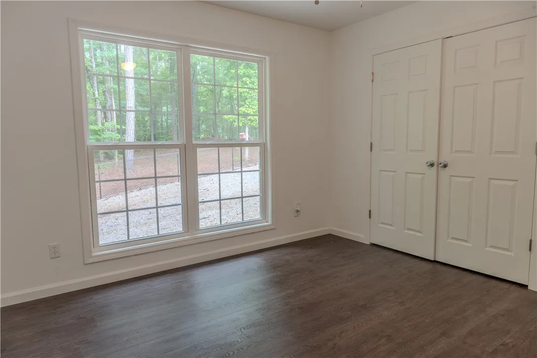 Hardwood-style flooring and dual closets enhance this bright, airy bedroom with a verdant outlook.