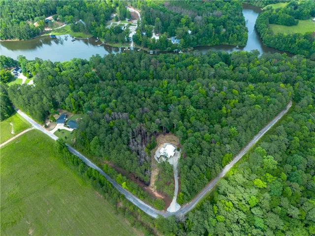 An aerial panorama showcases a secluded property nestled amidst a dense forest, boasting private lake access.