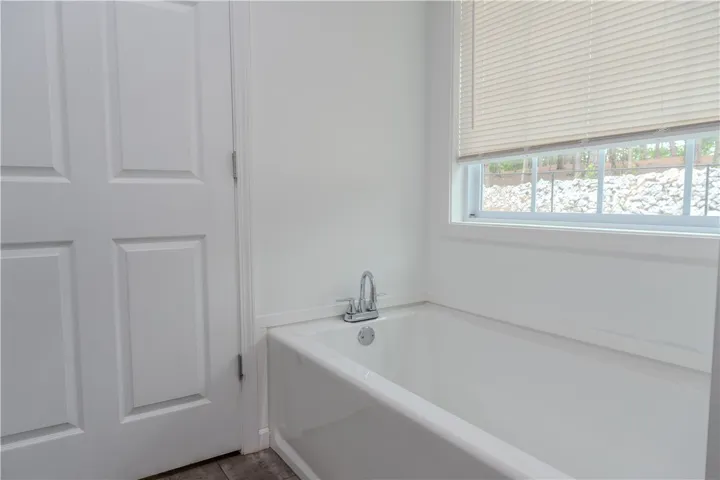 A pristine white bathtub offers a clean, inviting space with a window above.
