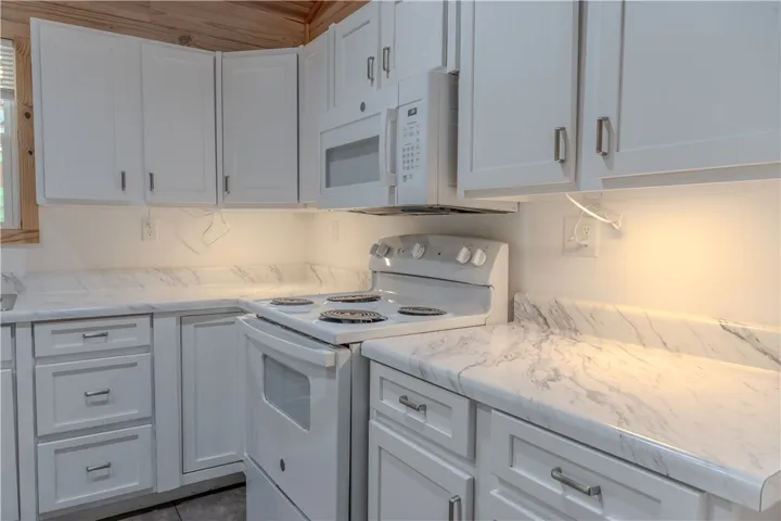 White cabinetry and marbled countertops highlight this compact yet efficient kitchen.