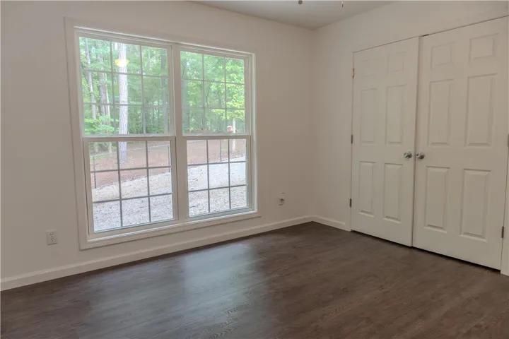 Hardwood-style flooring and dual closets enhance this bright, airy bedroom with a verdant outlook.