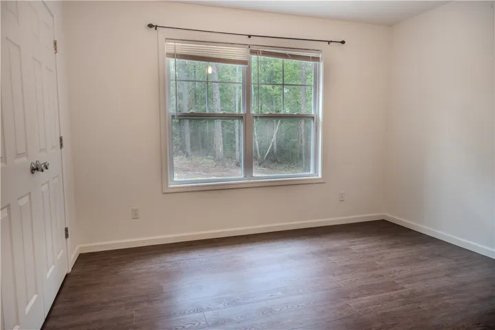Ample natural light illuminates rich hardwood flooring in this cozy bedroom.