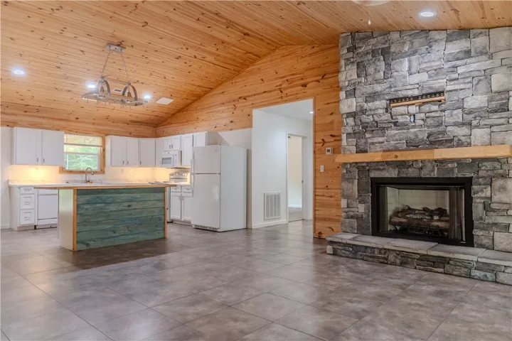 A spacious, naturally illuminated kitchen and living area feature a striking stone fireplace.