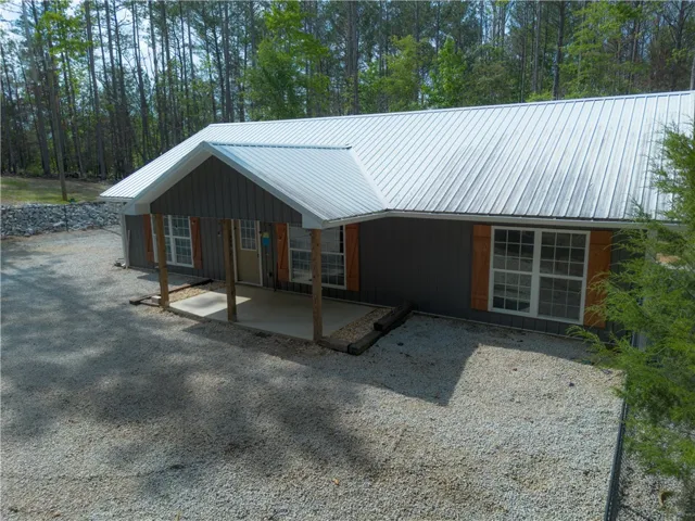 An inviting gravel driveway leads to this charming gray home with a durable metal roof.