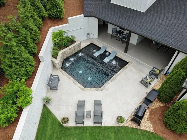 Private and tranquil backyard oasis features a glistening pool with cascading waterfalls and ample leisure space.