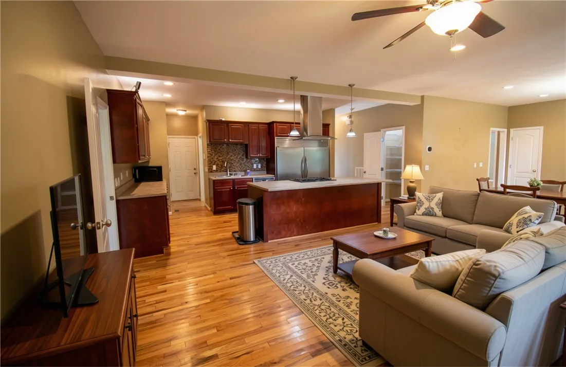 Virtually staged image - An inviting open-concept living space features hardwood flooring and a well-appointed kitchen with an island.