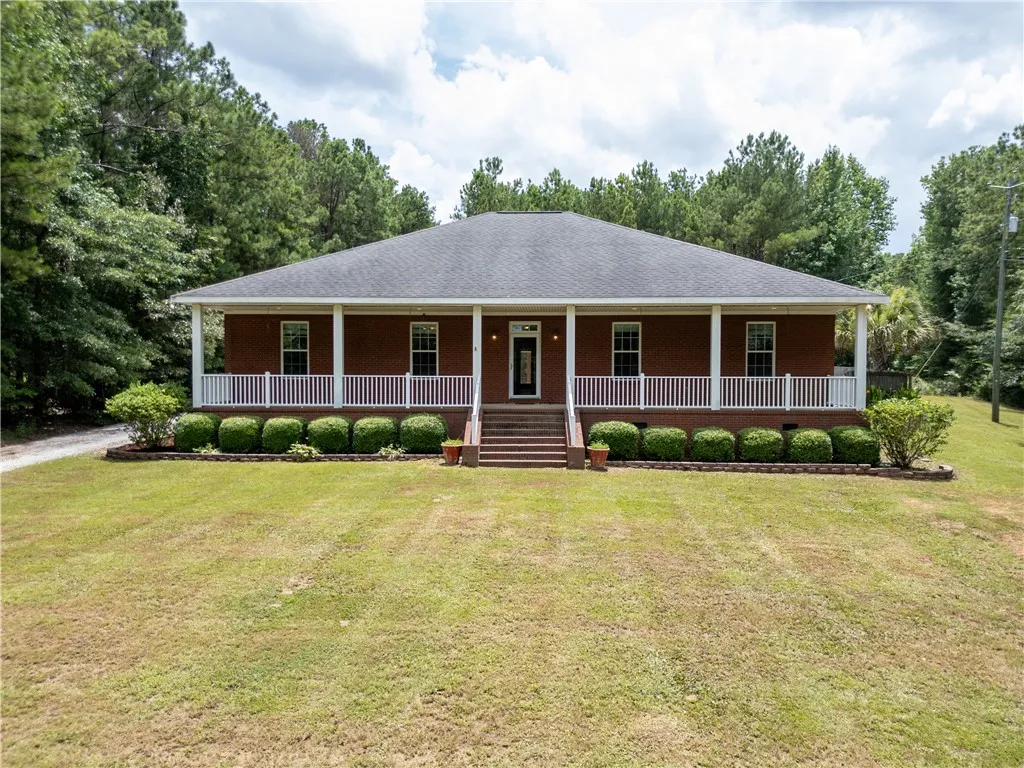 A classic brick facade welcomes you, framed by a full-length covered porch and mature landscaping.