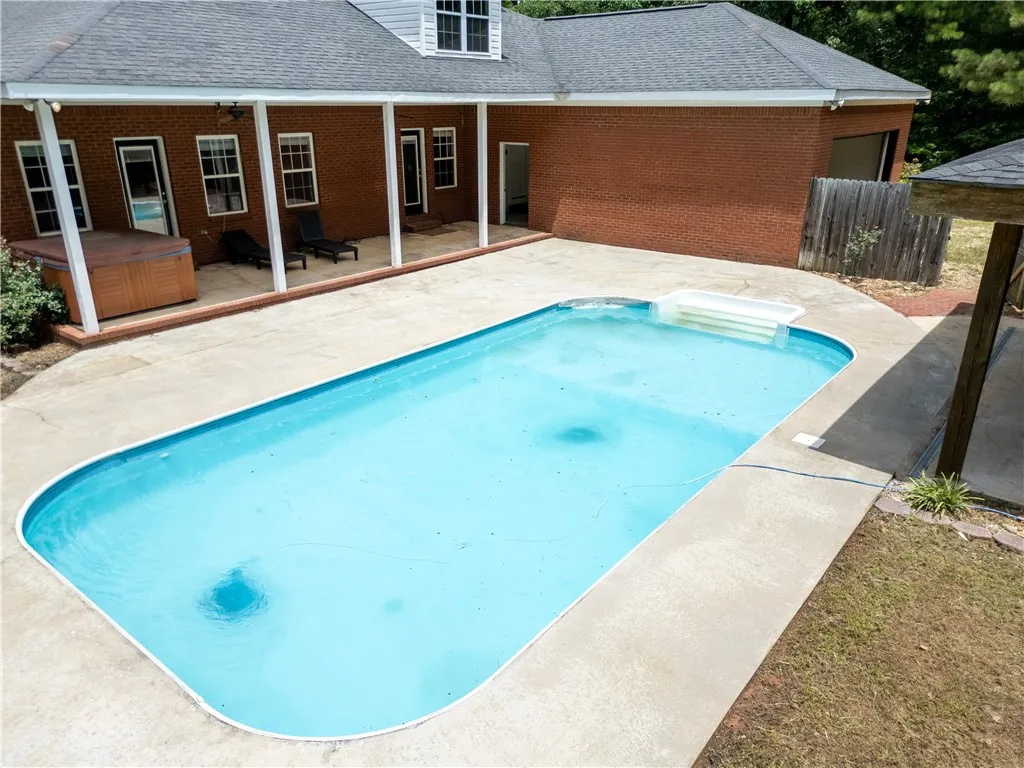 An inviting backyard oasis features a clear blue pool and a secluded hot tub, ideal for relaxation.