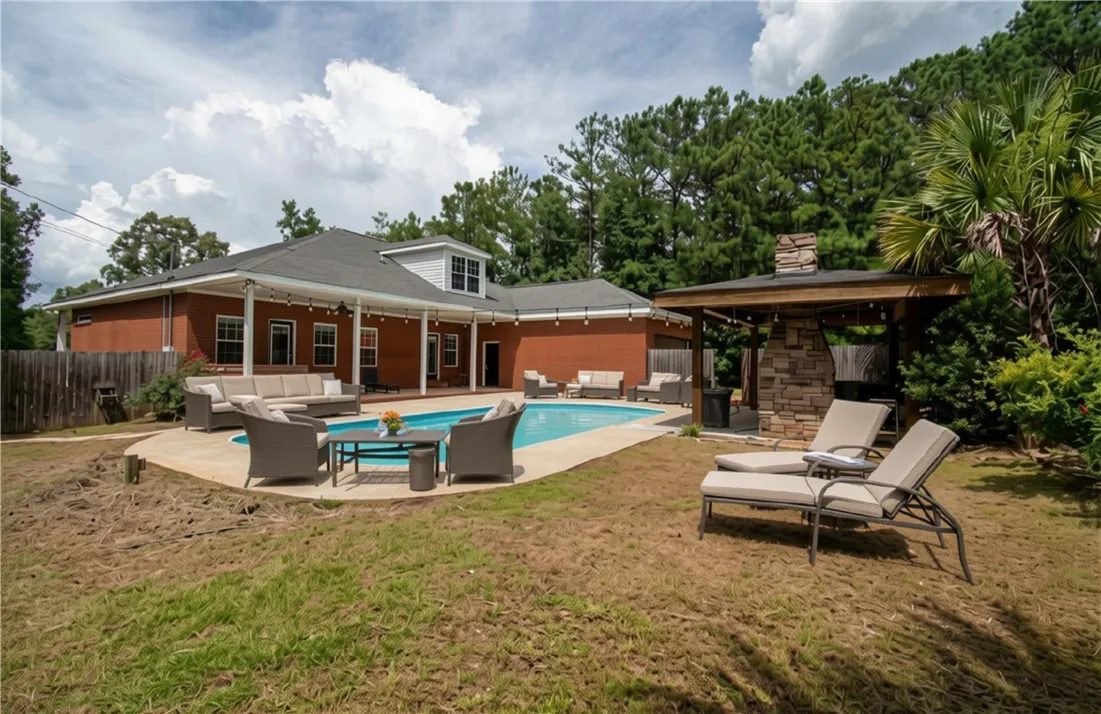 Virtually staged image - An inviting backyard oasis features a glistening pool alongside a covered outdoor kitchen and ample patio space for relaxation.