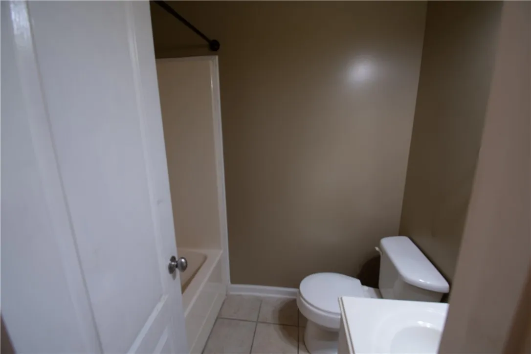 A well-maintained bathroom with a tub, toilet, and simple white vanity.