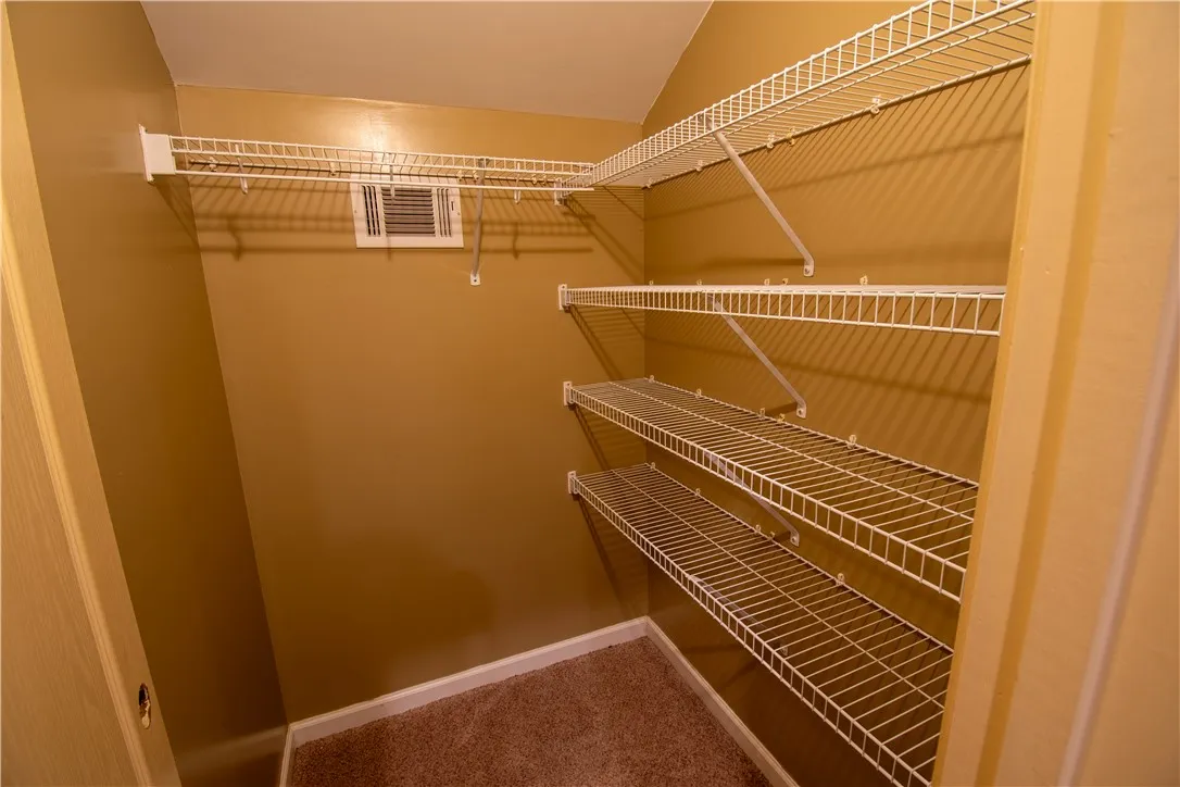 Ample wire shelving maximizes storage in this organized, carpeted walk-in closet.