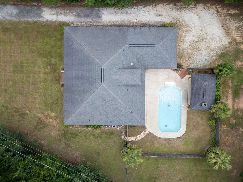 An aerial perspective reveals a private pool with ample surrounding patio space, nestled beside a well-maintained residence.