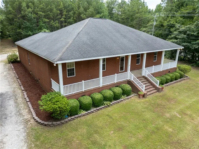 A classic brick exterior welcomes with a spacious porch and mature landscaping.