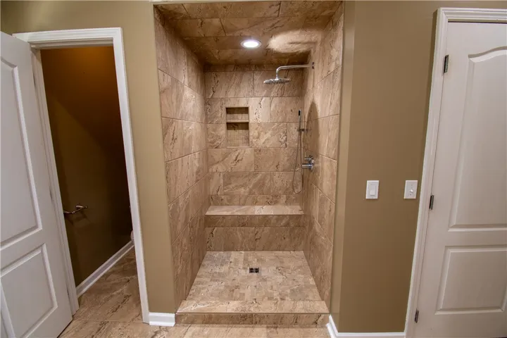 Indulge in this well-appointed walk-in shower, featuring a built-in bench and recessed lighting for a spa-like experience.