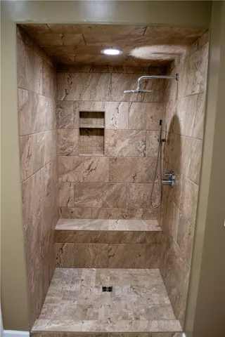 A spacious, naturally illuminated shower with elegant tiled walls and convenient seating.
