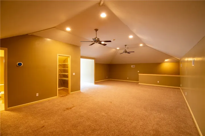 An adaptable attic space features sloped ceilings, recessed lighting, and soft carpet.