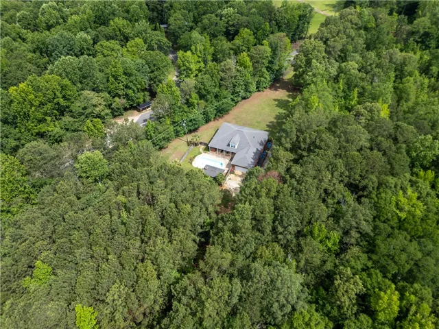 An aerial perspective reveals a secluded residence amidst a lush, verdant landscape with a private pool.