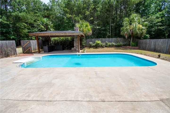 A private backyard oasis features a glistening pool and a sheltered outdoor kitchen area.