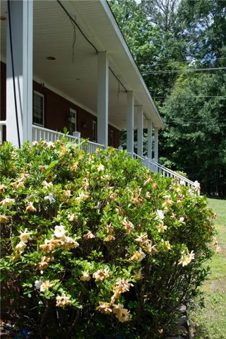 A welcoming front porch, shaded by mature trees, provides an inviting entry to this brick home.