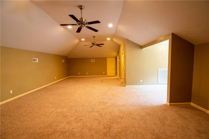 A spacious room offers comfortable carpet flooring and ample overhead lighting.